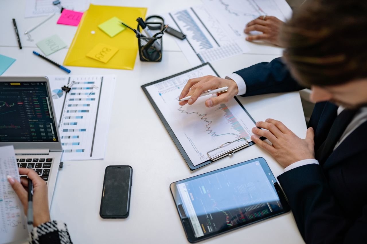 Mastering the First Impression: Your intriguing post title goes here Team reviewing financial charts and digital data on tablets in an office setting.